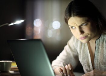 A young woman looking at a laptop screen, wondering “Is Truth Finder legit?