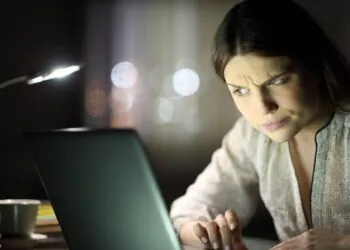 A young woman looking at a laptop screen, wondering “Is Truth Finder legit?